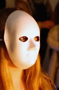 volto di una ragazza in primo piano coperto da una maschera bianca